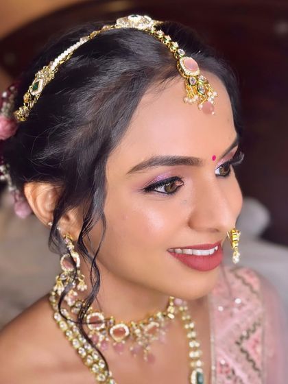A side profile showing the elegant updo with floral details and the delicate matha patti that frames her face beautifully.
