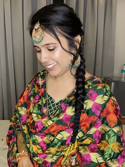 My beautiful bride is ready for her Jago function. She is wearing a traditional Punjabi suit with a colorful phulkari dupatta, and I created a natural look with a classic braid and paranda.
