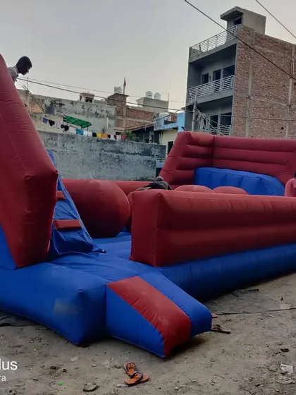 A side view of the 'Baller Game' obstacle course. You can see the raised platform for entry and the large, unstable balls that participants must cross.