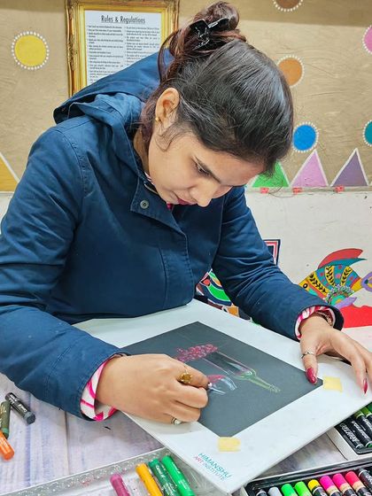 A student engrossed in her oil pastel artwork, surrounded by a vibrant array of colors.