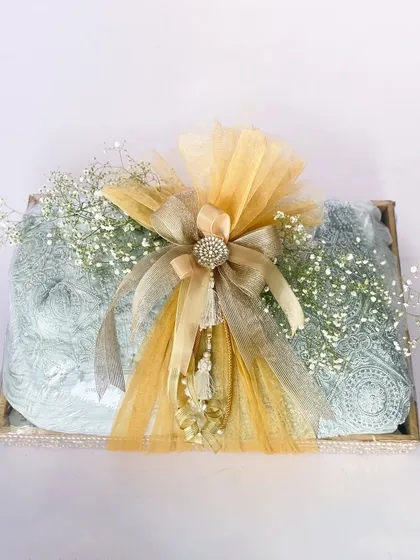 An elegant trousseau tray for a roka ceremony. The gifts are wrapped in a beautiful light blue fabric and tied with a lavish gold and silver bow.