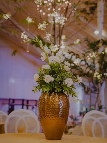Details make the design. This close-up shows a custom floral centerpiece with white roses and gladioli arranged in a hammered-gold vase, an example of the fine touches we add to our event decor.