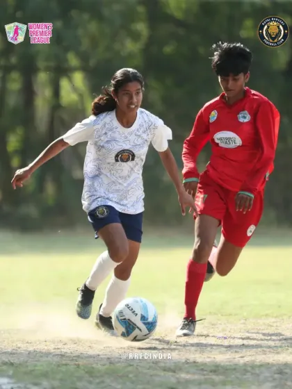 Our player dribbles forward with determination, keeping the ball close while being challenged by an opponent in red.