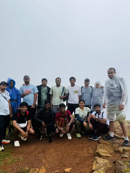 A group of trekkers at a summit, tired but happy after a long climb.