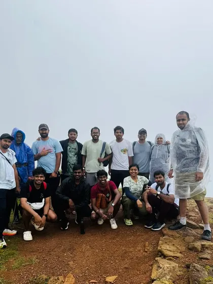 A group of trekkers taking a break at a viewpoint, with the sky and clouds creating a white, misty backdrop.