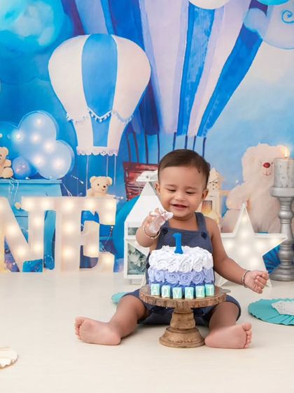 The first touch of the cake. I love capturing the curiosity and excitement in this moment, set against a dreamy blue sky backdrop with balloons and stars.