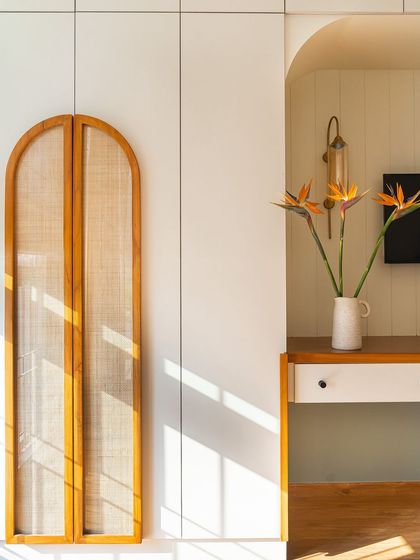 In this master bedroom, I used arched cane panels on the wardrobe doors, adding a touch of lightness and texture. The archway leading to the study nook continues this design motif.