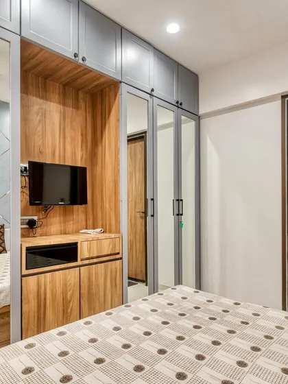 A view of the bedroom's functional layout, showing the bed, wardrobe, and integrated TV unit. Every element is designed to work together for a cohesive and comfortable space.