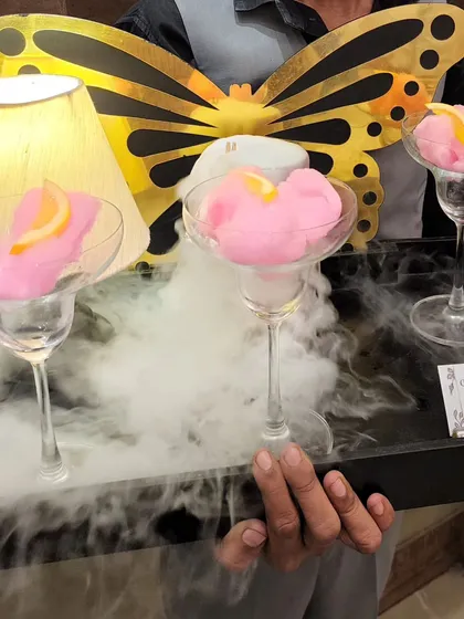 This is our signature Candyfloss Cosmo. We serve these magical cocktails on a tray billowing with smoke, creating a whimsical experience that tastes as good as it looks.