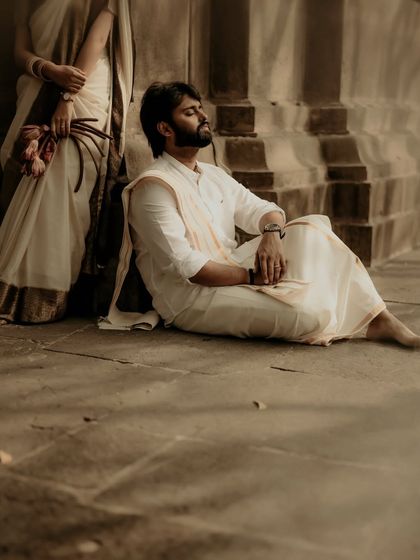 A thoughtful, artistic shot of the groom resting against ancient temple steps. The composition, with his partner just in frame, tells a story of shared peace and companionship.