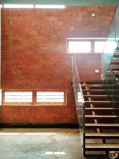 Natural light floods this double-height courtyard, highlighting the texture of the laterite brick accent wall. We designed this space with a modern floating staircase and large skylights to create a vibrant, sunlit core within the home.