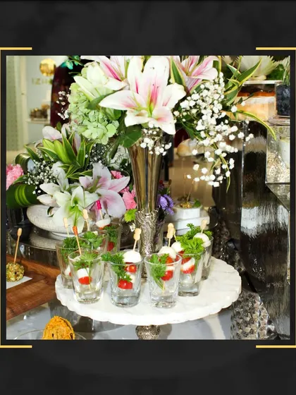 We elevate your event with exquisite tablescapes. This display features fresh caprese salad shooters, beautifully arranged on a marble platter amidst a stunning floral centerpiece.
