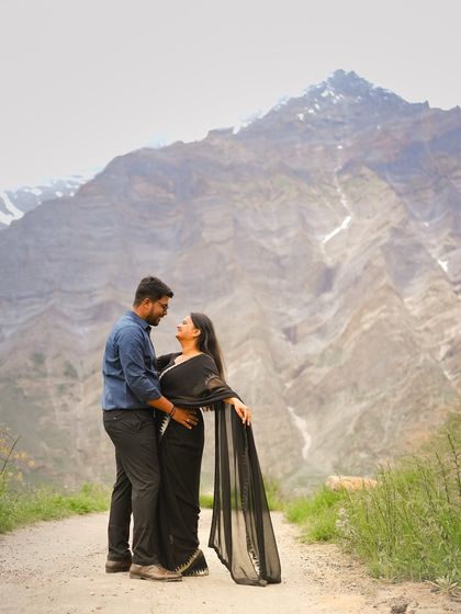 A classic romantic pose on a mountain road, with the couple lost in each other's eyes, framed by the towering peaks of Himachal.