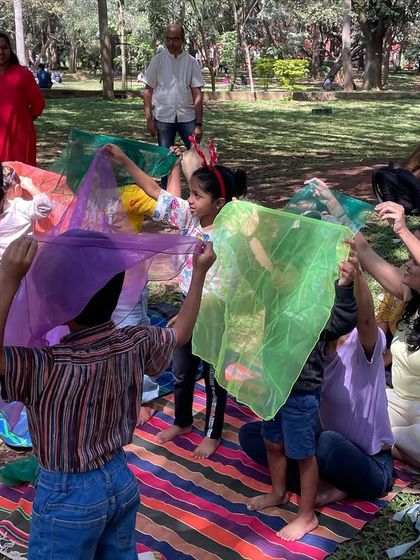 Children playing with colorful scarves, hiding and peeking through them. This sensory play activity is a perfect example of how we incorporate fun and movement into our workshops.