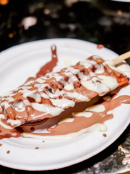 A waffle stick generously coated in milk and white chocolate, perfect for guests to enjoy on the go.