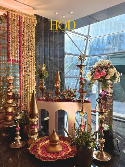 Close-up of the traditional decor elements at an entrance, showcasing stacked brass vessels and intricate floral arrangements that add layers of texture and culture.