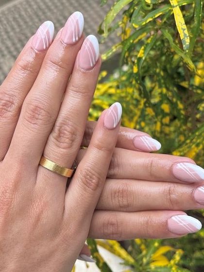 A chic and modern take on a nude manicure. This design features a soft pink base with clean, white asymmetrical lines for a minimalist yet stylish look.