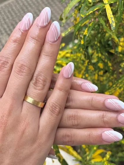 A chic and modern take on a nude manicure. This design features a soft pink base with clean, white asymmetrical lines for a minimalist yet stylish look.
