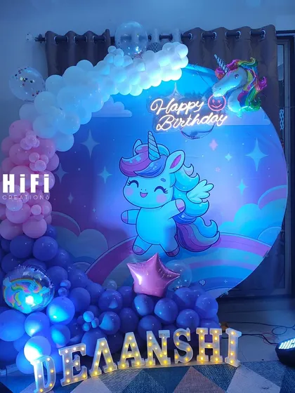 A dreamy unicorn-themed birthday party setup. We used a round backdrop with a cute unicorn graphic, a pastel and purple balloon arrangement, and marquee letters spelling out the birthday girl's name.