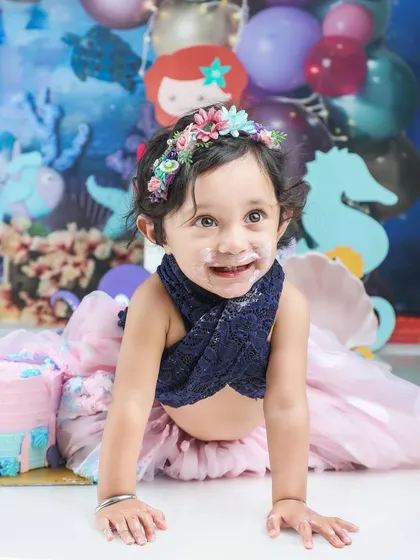 A little mermaid enjoying her first birthday cake. The under-the-sea theme makes this cake smash extra special.