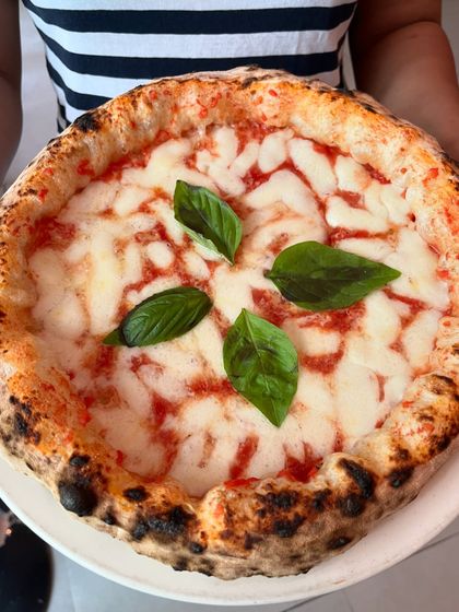 A perfect Margherita, held up by a happy customer. This is the sight we love to see.