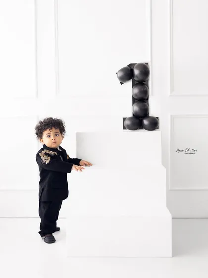 A full-length shot of our little gentleman standing proudly next to the number "1" made of balloons. A stylish and modern first birthday photo.