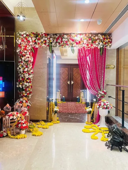 This is the entrance to a vibrant Haldi ceremony. I used a combination of pink drapes and marigold flower arrangements to create a festive and welcoming pathway for guests.