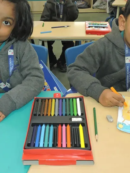 Two students collaborate on a craft project. We foster a supportive environment where children learn to work together and respect each other's abilities.