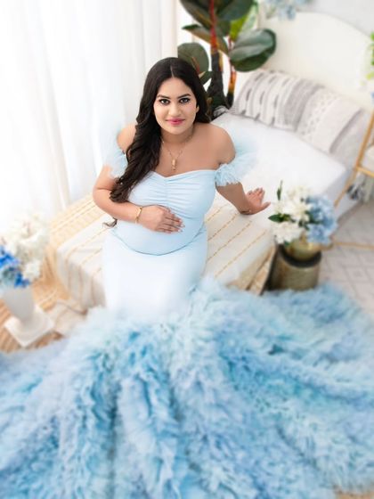 An overhead view that beautifully showcases the dramatic train of the ruffled gown. This artistic angle highlights the fashion element of the shoot while keeping the focus on the serene mother-to-be.