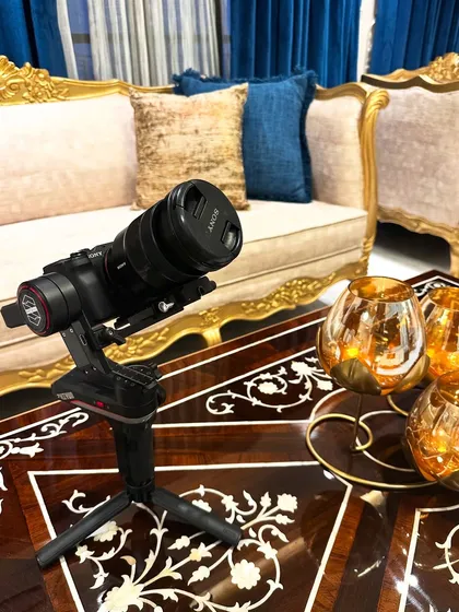 A photo of me with a camera, ready to shoot a project, set against a luxurious royal golden sofa.