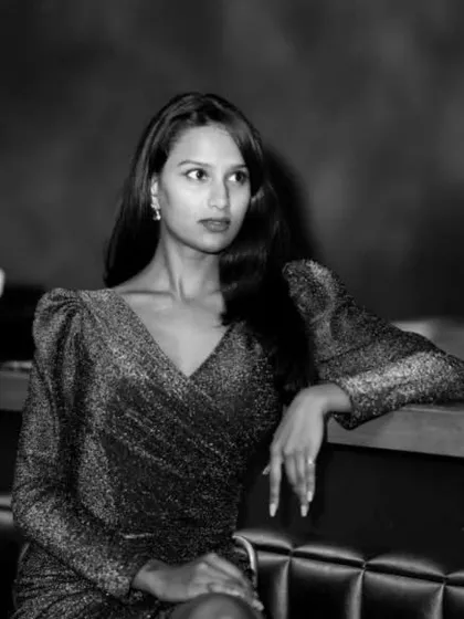 A timeless black and white portrait taken in a club, focusing on the model's thoughtful expression and the elegant silhouette of her dress.