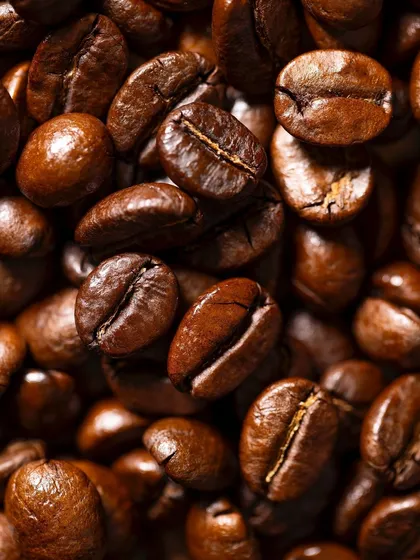 An extreme close-up macro shot of roasted coffee beans. This image was taken to capture the intricate textures, oils, and deep colors of the beans, showcasing technical camera skill.