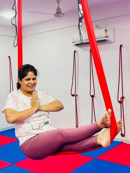 Finding comfort and peace in the hammock is a key part of our practice. This student holds a gentle seated pose, demonstrating the relaxing aspects of aerial yoga.