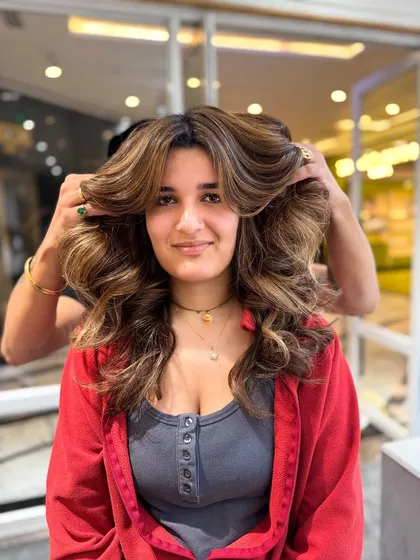 A happy client showing off her voluminous, no-bleach balayage transformation.