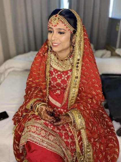 My beautiful Punjabi bride, dolled up for her Mangal Phere. The traditional red and gold outfit is complemented by a classic makeup look with smokey brown eyes.