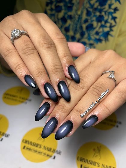 A deep and moody aura nail set. The black base fades into a smoky blue center, creating a mysterious and commanding look with a glossy finish.
