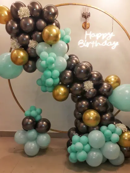I also design modern and chic decorations for birthdays. This setup features a stylish organic balloon arrangement in mint green, gold, and grey on a circular frame, complete with a 'Happy Birthday' neon sign.