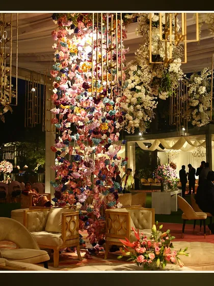 A lounge area with a dramatic, multi-colored floral installation hanging from the ceiling, creating a vibrant and artistic focal point.