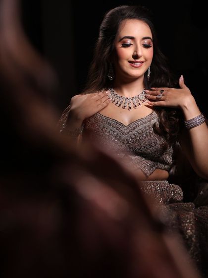 Admiring the final look in the mirror. This reflective shot captures the intricate details of her jewelry and the soft, glowing finish of her engagement makeup.