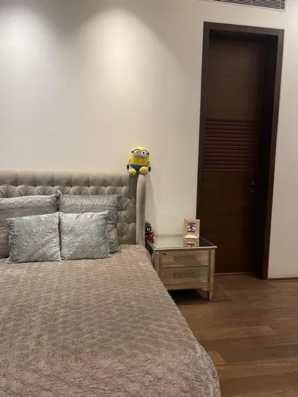 A close-up of the bedside area, featuring a tufted headboard that adds a touch of classic luxury. The simple, clean-lined nightstand provides functionality without cluttering the serene space.