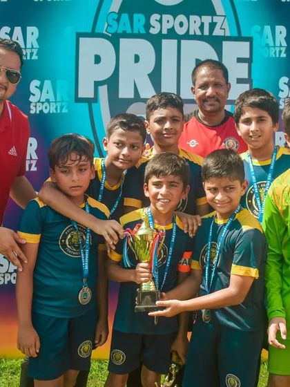 Another victorious team poses with their medals and trophy after a successful tournament.