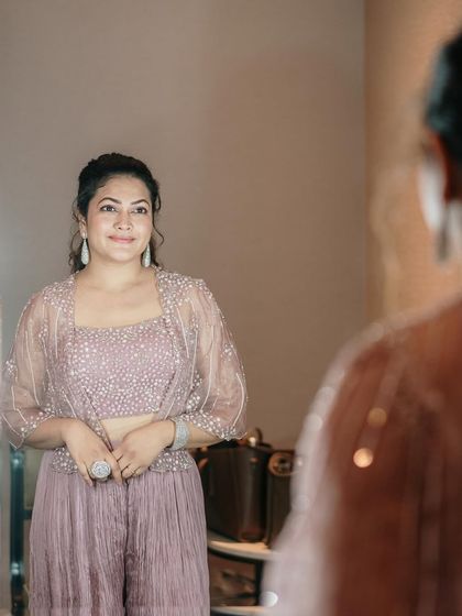 A mirror shot capturing the details of the embellished crop top and sheer cape.