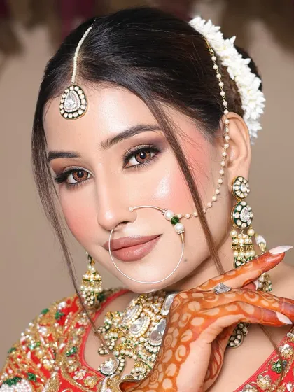 This student created a soft, dewy bridal look with a focus on glowing skin and subtle brown smokey eyes. The hair is styled in a bun with fresh flowers.