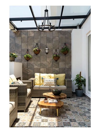 The stunning outdoor lounge on the balcony, featuring comfortable wicker furniture and a feature wall of brownish-grey tiles. The space is perfect for hosting friends or enjoying a quiet afternoon.