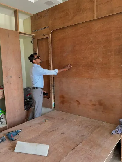A full view of a bedroom during the carpentry phase, with the bed and wardrobe structures being built.