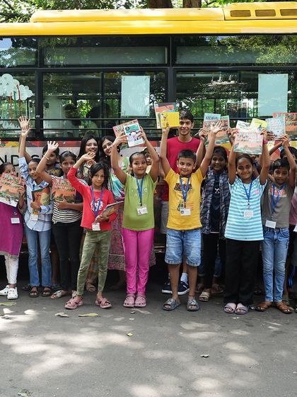 The children wave happily with their new books after a fun-filled session on the music bus.