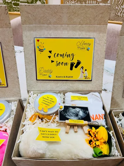 This box includes a custom onesie for 'Nani', a soft toy, and a tin of cookies with the message, "We are baking more than just cookies."