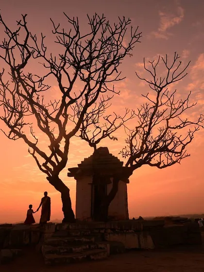 A beautiful silhouette of a mother and child against the warm glow of a Hampi sunset, framed by a stark, ancient tree. This image tells a quiet story, blending landscape and human elements perfectly.