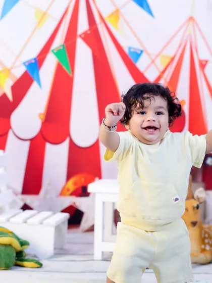 A moment of pure joy as a one-year-old throws his hands up in excitement during his carnival-themed birthday shoot.