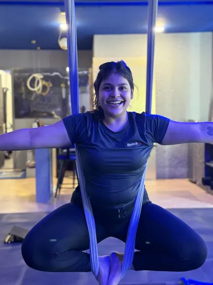The pure joy of flying. This member's bright smile captures the fun and liberating feeling of an aerial yoga class.
